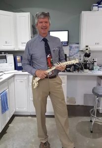 dr mulch holding an example spine and posing in vet office